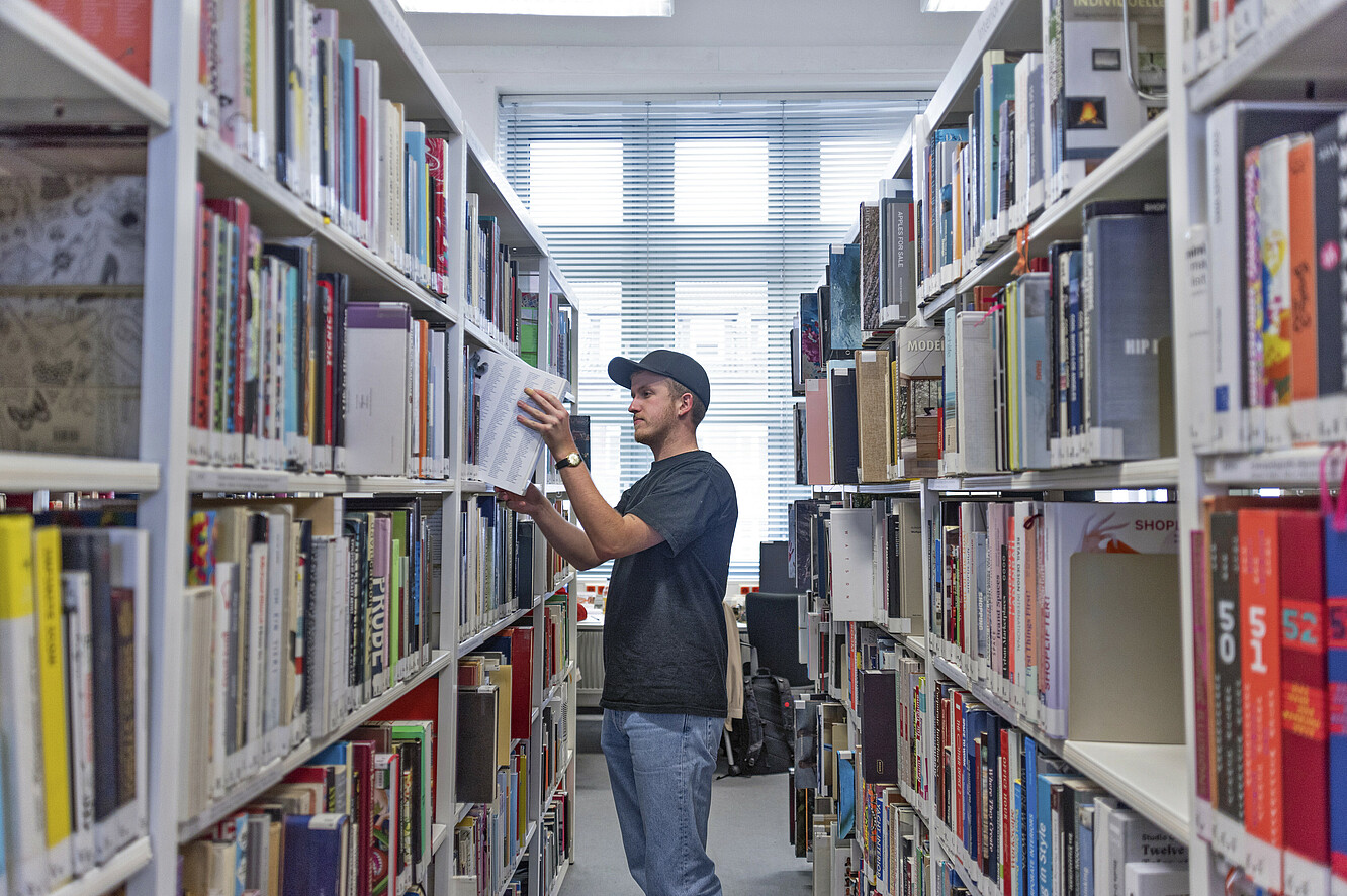 Foto eines Studierenden in der Bibliothek am Fachbereich Gestaltung